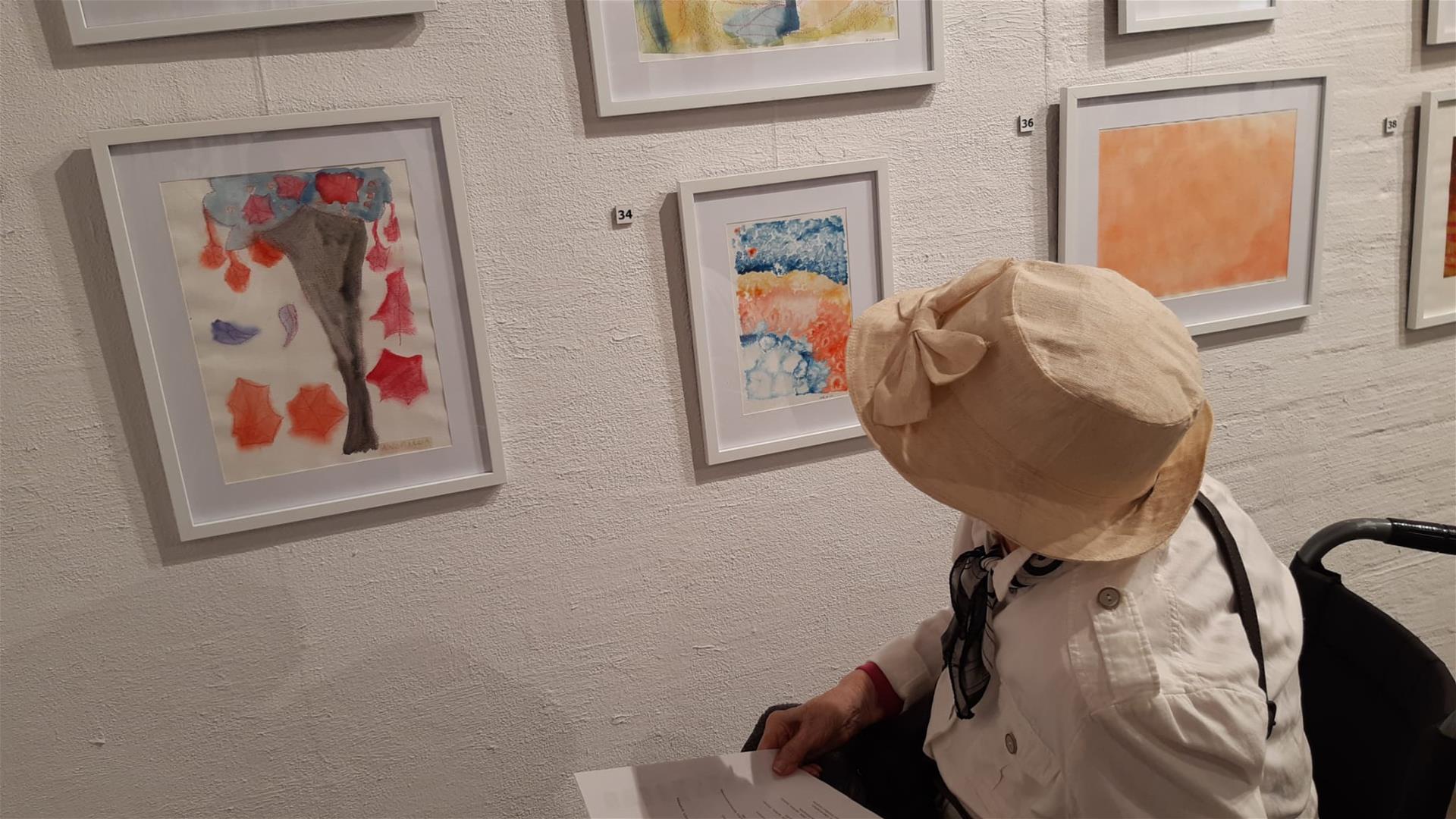 Hattupäinen henkilö katselee taidenäyttelyä.